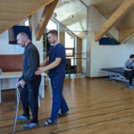 A physical therapist at Agape Rehabilitation Center, Ukraine, helps a man walk.