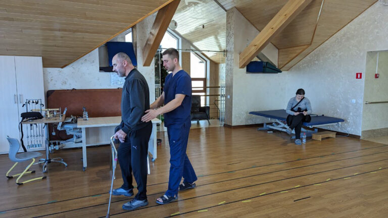 A physical therapist at Agape Rehabilitation Center, Ukraine, helps a man walk.