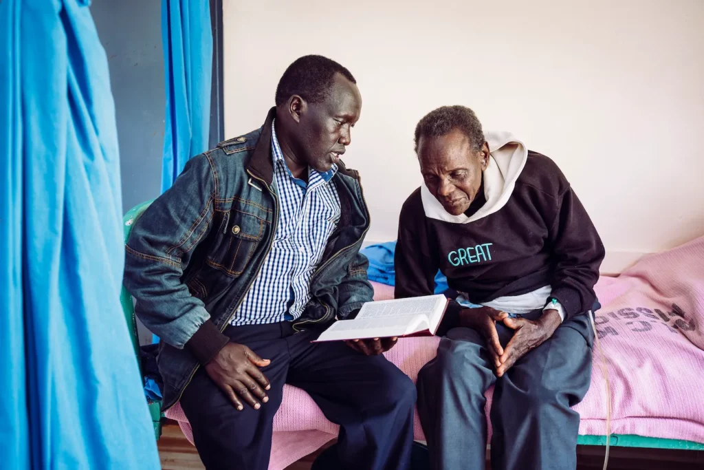 Man offering spiritual care by reading Scripture with a hospital patient