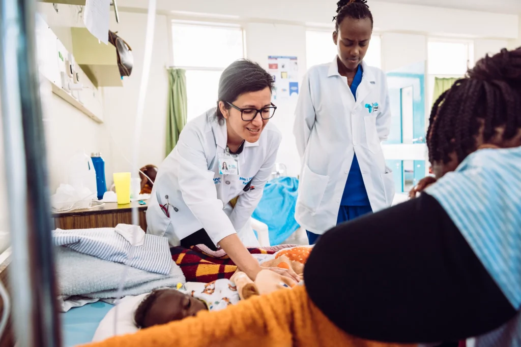 Doctors examining a young child with a parent in a hospital ward
