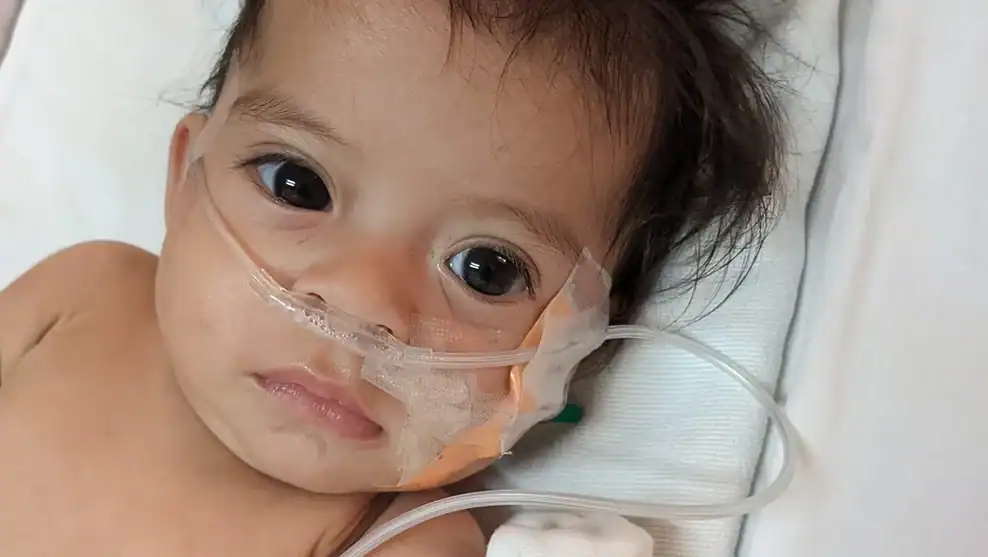 Baby in hospital with nasal cannula for oxygen while recovering